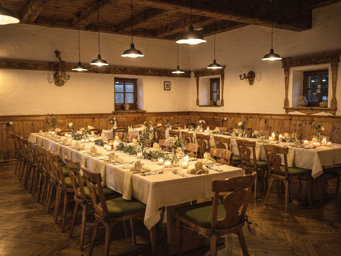 Festlich eingedeckter Festsaal mit langer Tafel und Hängeleuchten